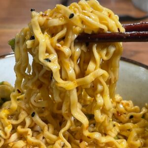 Bowl of noodles with sauce and chopsticks