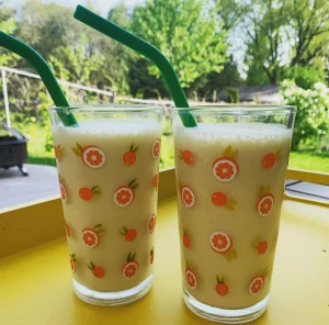 Two glasses with green straws. Orange Julius in a glass