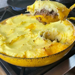 A spoonful of Shepherd's pie over a pan of shepherd's pie