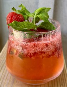 strawberry shrub in a rocks glass garnished with fresh mint