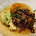 braised beef on a plate with pickled carrot