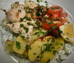chicken souvlaki plated with greek lemon potatoes and tzatziki sauce